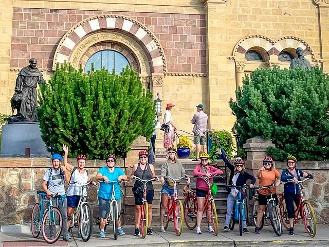 Un groupe de cyclistes posant avec leurs vélos devant une église en pierre.