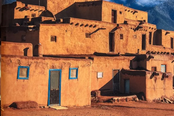 Ein mehrstöckiges traditionelles Adobe-Gebäude mit blauen Zierleisten, das warm im Sonnenlicht leuchtet.
